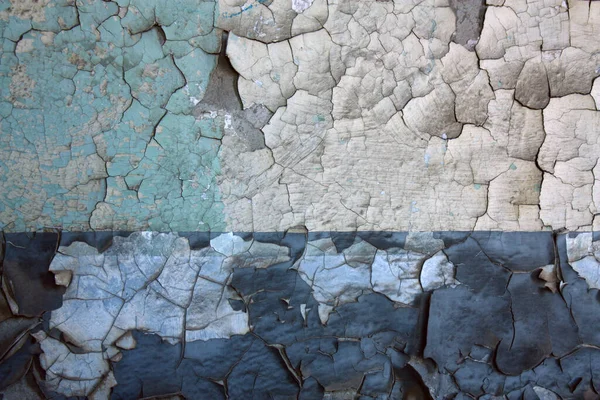 Старая потрескивающая краска на двухтонированной стене показывает бетонную стену под ней. — стоковое фото