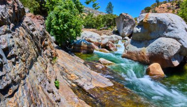 Canlı bir manzara Orta Çatal Kaweah Nehri 'ni yakalıyor Sequoia Ulusal Parkı' ndaki devasa kayaları ve gür ağaçları geçiyor parlak mavi bir yaz gökyüzünün altında..