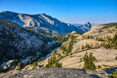 Granit yamaçlar ve dağınık çam ağaçları Yosemite Olmsted Point 'in geniş bir görüntüsünü oluşturuyor. İkonik Yarım Kubbe, California' nın berrak gökyüzünün altında yükseliyor..