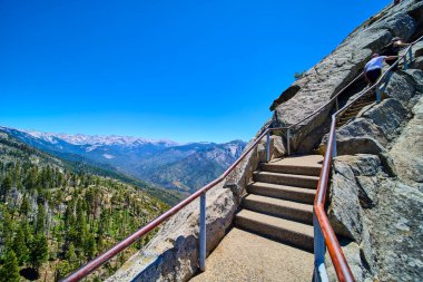 Güneşli taş merdiven Sequoia Ulusal Parkı 'ndaki Moro Kayası' nda açık bir yaz gününde Sierra Nevada dağları ve yemyeşil orman vadisinin geniş manzarasıyla doluyor..