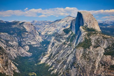 Sunlit Half Dome, Kaliforniya 'daki Buzul Noktası' ndan görülen Yosemite Vadisi 'nin üzerinde dramatik granit kayalıkları ve açık yaz gökyüzü ile dimdik duruyor..