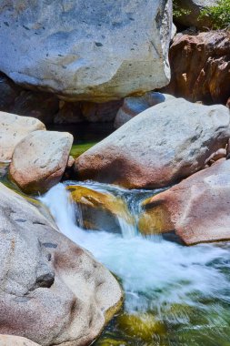 Orta Çatal Kaweah Nehri Sequoia Ulusal Parkı 'ndaki dev granit kayalar arasında akar. Güneş ışığı berrak suyu yansıtır ve canlı ve doğal bir manzara yaratır..