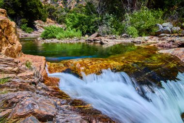 Orta Çatal Kaweah Nehri 'nde gün ışığı parıldıyor. Sequoia Ulusal Parkı' ndaki yeşil ağaçlarla çevrili kayalık kenarlardaki temiz su çağlayanı gibi. Saf ve doğal bir doğanın özünü yakalıyor.