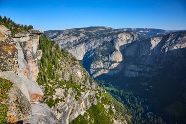 Granit kayalıklar ve gür çam ormanları, Yosemite Ulusal Parkı California 'daki Buzul Noktası' ndan Amerika Birleşik Devletleri 'nin vahşi doğasının özünü yansıtan açık mavi gökyüzünün altında bir araya geldiler.