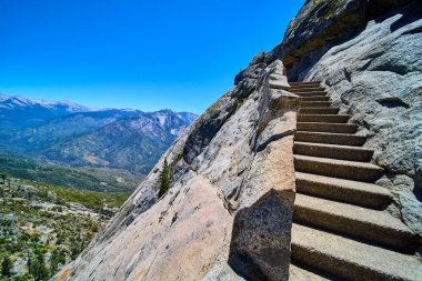 Taştan merdiven Sequoia Ulusal Parkı 'ndaki Moro Kayası' na vuruyor Kaliforniya engebeli granit kayalıkların nefes kesici manzaralarını sunuyor ve açık mavi gökyüzü altında Sierra Nevada dağlarını süpürüyor..