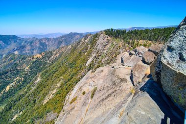 Moro Kayası 'nın güneşli granit kayalıkları Sequoia Ulusal Parkı' ndaki yemyeşil ormanların ve uzak dağların üzerinde yükseliyor. Kaliforniya 'da doğa ve macera dramatik bir manzara sunuyor..