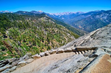 Taş basamaklar Sequoia Ulusal Parkı 'nda Moro Rock Yolu' na çıkar. Çam ormanlarının panoramik manzarası ve parlak mavi Kaliforniya gökyüzünün altındaki Sierra Nevada dağları..