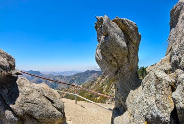 Granit kaya oluşumları Sequoia Ulusal Parkı 'ndaki Moro Kayası' nda manzaralı bir yürüyüş yolu çiziyor. Açık mavi gökyüzünün altındaki Sierra Nevada dağlarının panoramik manzarası..