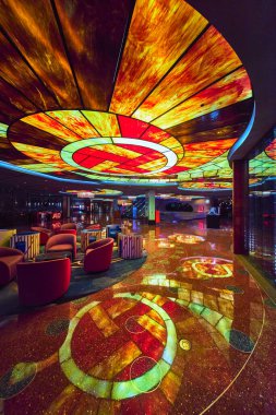 Aydınlatıcı tavan sanatı şık bir Las Vegas kumarhane salonunun cilalı zeminine yansıyor. Pahalı koltuklar ve canlı dekorlar Strip 'te enerjik ve lüks bir hava yaratıyor..