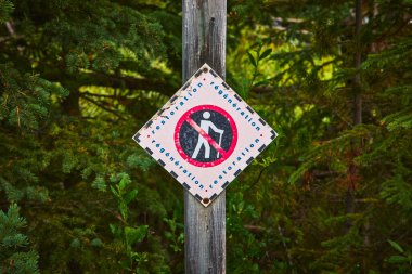 Jasper Kanada 'da Maligne Gölü yakınlarındaki yoğun yeşil yaprakların önünde duran bir restorasyon tabelası, koruma çabalarının altını çiziyor ve göl ve orman ortamını korumak için erişime kısıtlama getiriyor..