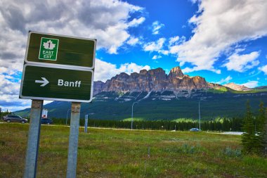Yeşil otoyol tabelası Banff 'ı, Kanada dağlarında dramatik dağlar ve yaz bulutları olan ve seyahat ve macera teması için mükemmel olan yoğun bir yol boyunca işaret ediyor..