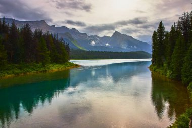 Jasper Kanada 'daki Maligne Gölü' nün sakin suları her zaman yeşil olan ormanları ve kasvetli bir gökyüzünün altındaki dramatik dağ zirvelerini yansıtır. Huzurlu ve dehşet verici doğal bir manzara yaratır..