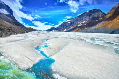 Jasper Kanada 'daki Athabasca Buzulu' ndan geçen parlak erimiş su akıntıları engebeli dağ zirveleri ve çarpıcı ve ferahlatıcı bir doğal manzara yaratan canlı mavi gökyüzü tarafından çerçevelenmiştir..