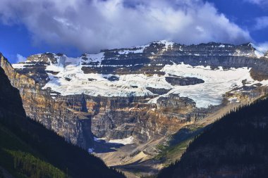 Görkemli buzullar ve engebeli dağlar Banff 'taki gür orman vadilerinin üzerindeki doğal güzelliği vurgulayan dramatik bulutlar ve canlı renkler ile Louise Gölü' nün yakınındaki vadilere hakimdir.