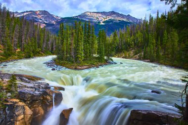 Sunwapta Şelaleleri 'nde çağlayan sular, yemyeşil çam ormanları ve Jasper Kanada' da yükselen dağlarla çevrilidir. Bu ikonik vahşi doğanın el değmemiş güzelliğini ve güçlü enerjisini yakalar..