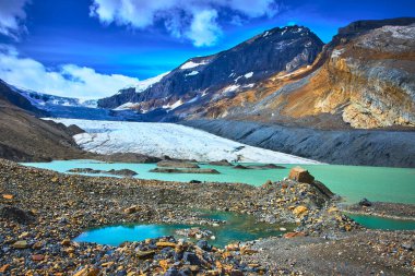 Turkuaz eriyen su havuzları ve engebeli kayalar etkileyici Athabasca Buzulu 'nu ve Jasper Kanada' daki dramatik dağ manzarasını canlı bir gökyüzü altında çevreleyecek..