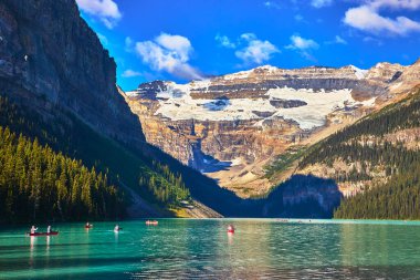 Kanolar ve kanolar, Banff Kanada 'da buzul dağları ve çam ormanlarıyla çevrili turkuaz göl üzerinde yüzerler. Temiz, doğal bir ortamda macera ve sükuneti davet ederler..