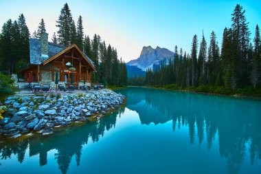 Yoho 'daki Zümrüt Gölü' nün kıyısındaki rahat bir kulübe orman ve sakin suyla çevrilidir. Altın saatinde dağları yansıtan sakin ve davetkar bir manzara yaratır..