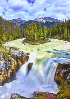 Jasper Canada 'daki Sunwapta Şelalesi' nde akan sular, her yer yeşil ağaçlarla ve çarpıcı dağlarla çevrili. Titrek bir gökyüzü altında nefes kesici bir doğal manzara yaratıyor..