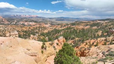 Hava izleme görüntüleri Bryce Kanyonu 'nun üzerinde süzülüyor Utah' ta dramatik kaya oluşumlarını yakalıyor çam ormanları ve çöl manzaralarını parlak bir öğle vakti gökyüzü altında korku ve macera hissi için..