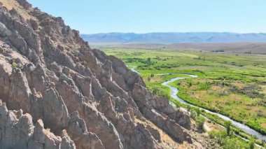 Cokeville Wyoming 'deki Legion Park' taki kayalık tepenin üzerinden geçen hava uçuşu kıvrımlı bir nehri ve aşağıdaki yeşil vadiyi ortaya çıkarıyor. Parlak gökyüzü ve geniş manzaralar ilham verici bir his yaratır.