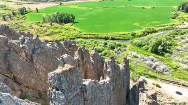 Cokeville Wyoming 'deki Legion Park' taki dramatik kaya oluşumlarının üzerinden geçen hava uçuşu dolambaçlı bir nehir ve yemyeşil alanlar ortaya çıkarıyor. Parlak yaz ışığı doğanın güzelliğini ve hissini arttırır.