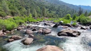 Kaliforniya 'daki El Portal Nehri boyunca uçan manzara dağlarla çevrili su kayaları ve yoğun yeşil ormanı yakalar ve macera için mükemmel bir dinamik kurgu sahnesi yaratır.