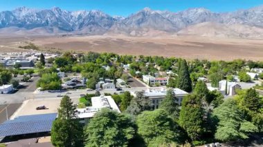Independence California 'nın hava manzarasında, yemyeşil ağaçlarla çevrili küçük kasaba sokakları ve ötesinde Sierra Nevada dağları olan açık çöl bulunur. Kamera yörüngeleri benzersiz karışımı ortaya çıkarmak için