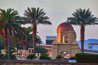 Palmiye ağaçları Las Vegas Nevada 'da akşam saatlerinde bir Akdeniz kubbesi ve parlayan ışıklar çerçeveler. Verimli peyzaj ve imza mimarisi hoş ve lüks bir tatil yeri ortamı yaratıyor.
