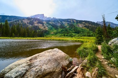 Bereketli yeşil ormanlarla çevrili Moose Pond 'un huzurlu manzarası ve Wyoming' deki engebeli Grand Teton dağları doğa ve seyahat için ideal sakin bir atmosfer yaratıyor..