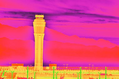 Las Vegas havaalanındaki bir hava trafik kontrol kulesinin canlı kızılötesi görüntüsü gün doğumunda çöl dağlarına karşı duruyor. Kalın renkler ve altın saat ışığı yenilik ve yolculuk çağrıştırıyor