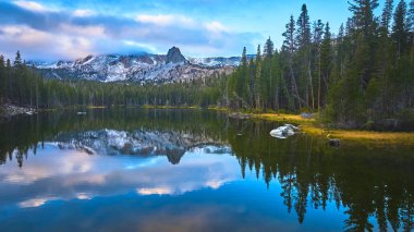 Çam kulesi, sakin bir dağ gölünün etrafını sarar. Karlı tepeleri ve dramatik gökyüzünü yansıtır. Barışçıl ruh hali ve doğal güzellik Mamut ve İkiz Şelaleler 'in ruhunu çağrıştırıyor..