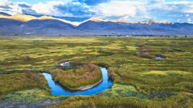 Owens Nehri 'nin havadan manzarası California' nın doğusundaki Bishop yakınlarındaki canlı sulak alanlarda kıvrılıyor. Güneşli dağlar ve geniş çayırlar, barışçıl ve ilham verici bir doğal ortam yaratır.