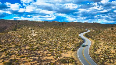 Cennete yakın Kaliforniya 'nın dolambaçlı bir yolundaki kurak çöl manzarasında dramatik bir gökyüzü altında tek bir araç seyahat ediyor. Sahne macerayı yakalar ve...