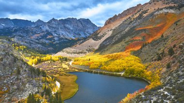 Kaliforniya 'nın Doğu Sierra bölgesindeki Kuzey Gölü' nün berrak mavi sularını çevreleyen canlı yapraklar. Dramatik dağ zirveleri ve renkli ağaçlar Piskopos yakınlarında çarpıcı bir sonbahar manzarası yaratır..