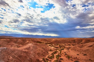 Engebeli kırmızı kaya oluşumları ve seyrek bitki örtüsü bu muhteşem Nevada çöl manzarasını tanımlıyor. Dramatik bulutlar ve güneş ışınları ABD 'deki Ateş Vadisi ve Moapa Vadisi' ni aydınlatıyor..