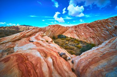 Canlı kumtaşı oluşumları Moapa Vadisi yakınlarındaki Muddy Dağı 'nda hakim. Çöl bitkileri ve dramatik bulutlar çarpıcı ve zamansız bir doğal manzara yaratır..