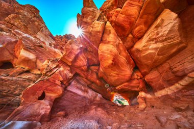 Parlak güneş ışığı Nevada Çölü 'nde çarpıcı bir doğal kemerin içinden geçiyor. Etrafı renkli Muddy Dağı kayaları ve engebeli Bitter Springs patikası dokularıyla çevrili. Sıcak tonlar ve kalın şekiller oluşturur
