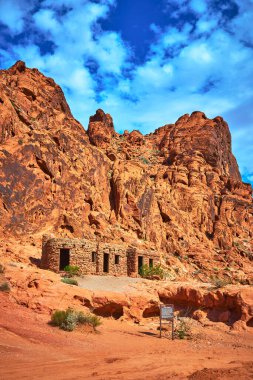 Kulübe Nevada Ateş Vadisi 'ndeki dramatik kırmızı kumtaşı uçurumlarının dibinde yer alıyor. Dağınık bulutlu parlak mavi gökyüzü bu ikonik Moapa Vadisi manzarasını tamamlıyor..