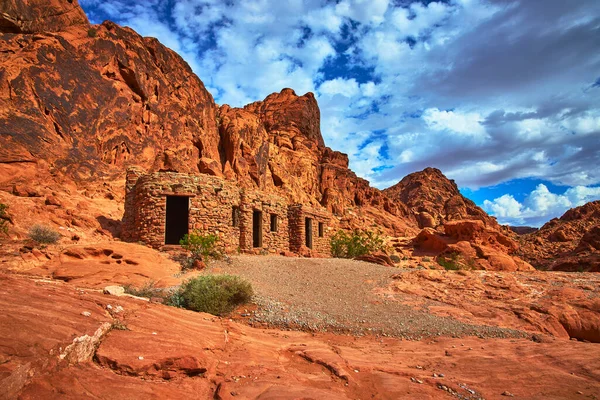 Kulübe Nevada Ateş Vadisi 'nde dramatik bir gökyüzünün altında canlı kırmızı kumtaşı uçurumlarının arasında yer alıyor. Tarihi taş işçiliği ve engebeli çöl arazisi Moapa Vadisi yakınlarındaki eşsiz manzarayı vurguluyor.