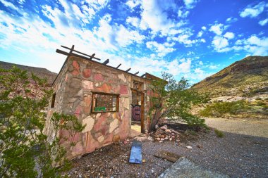 Nevada Çölü 'nde Muddy Dağı ve Moapa Vadisi yakınlarında renkli taşlardan yapılmış terk edilmiş bir bina var. Güneş ışığı, Color Rock Quarry 'nin engebeli arazisini ve seyrek bitki örtüsünü vurguluyor