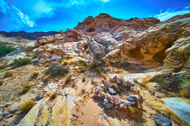 Güneş ışığı kumtaşı oluşumları Nevada çölünün göbeğindeki el yapımı kamp ateşi ve sığ mağaraların üzerinde yükselir. Canlı renkler ve açık gökyüzü Çamurlu Dağ yakınlarındaki Moapa Vadisi 'nde macerayı çağrıştırıyor.