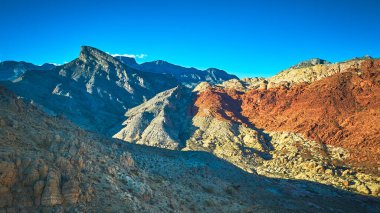 Nevada 'daki Kızıl Kaya Kanyonu' nun havadan görünüşü. Turtlehead Tepesi ve canlı kırmızı kumtaşı oluşumları Las Vegas yakınlarındaki açık mavi gökyüzünün altında çöl manzarasına karşı duruyor..