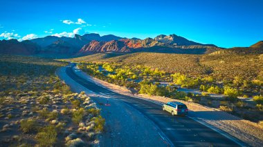 Las Vegas Nevada yakınlarındaki Red Rock Kanyonu 'ndan geçen hava manzaralı bir yol. Engebeli Kaplumbağa Tepesi dağlarına doğru ilerleyen bir araba..