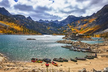 California, Doğu Sierra 'daki Sabrina Gölü' nün rıhtımında kano ve botlar sıraya dizildi. Sonbahar renkleri dağ yamaçlarında parlarken bulutlar gölde ve limanda dramatik bir ışık yaratıyor..