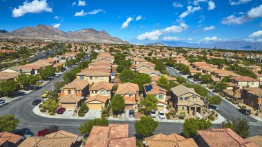 Las Vegas Nevada 'da dağlarla ve açık mavi gökyüzüyle çevrili bir yerleşim bölgesinin havadan görüntüsü. Banliyö evleri ve manzaralı çöl manzaraları canlı ve hoş bir manzara yaratır..