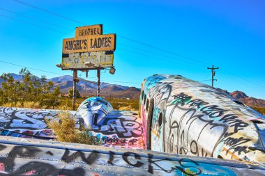 Nevada çölünde terk edilmiş bir duvar yazısıyla kaplı bir uçak Beatty yakınlarında solmuş Angels Ladies genelevinin altında duruyor. Güneşli dağlar ve kuru manzara bu eşsiz Birleşik Devletler yol kenarını çevreledi.