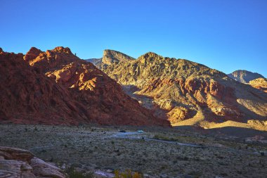 Calico Hills 'in kırmızı kumtaşı Las Vegas Nevada yakınlarındaki Red Rock Kanyonu' ndaki engebeli Turtlehead Tepesi 'ne zıt düşüyor. Açık gökyüzü ve çöl manzarası dramatik ve ilham verici bir doğal yaratıyor.