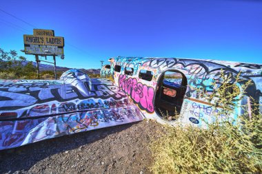 Grafiti ile kaplı parlak boyalı bir uçak gövdesi Beatty Nevada 'da bir genelevin yanında duruyor. Çöl manzarası ve cesur renkler Amerika 'da çarpıcı bir yol kenarı cazibesi yaratıyor.