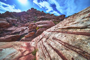 Las Vegas Nevada yakınlarındaki Kızıl Kaya Kanyonu 'nda Kraft Dağı yükselirken renkli kumtaşı çizgileri göze çarpıyor. Güneş ışığı eşsiz çöl jeolojisini ön plana çıkarıyor.